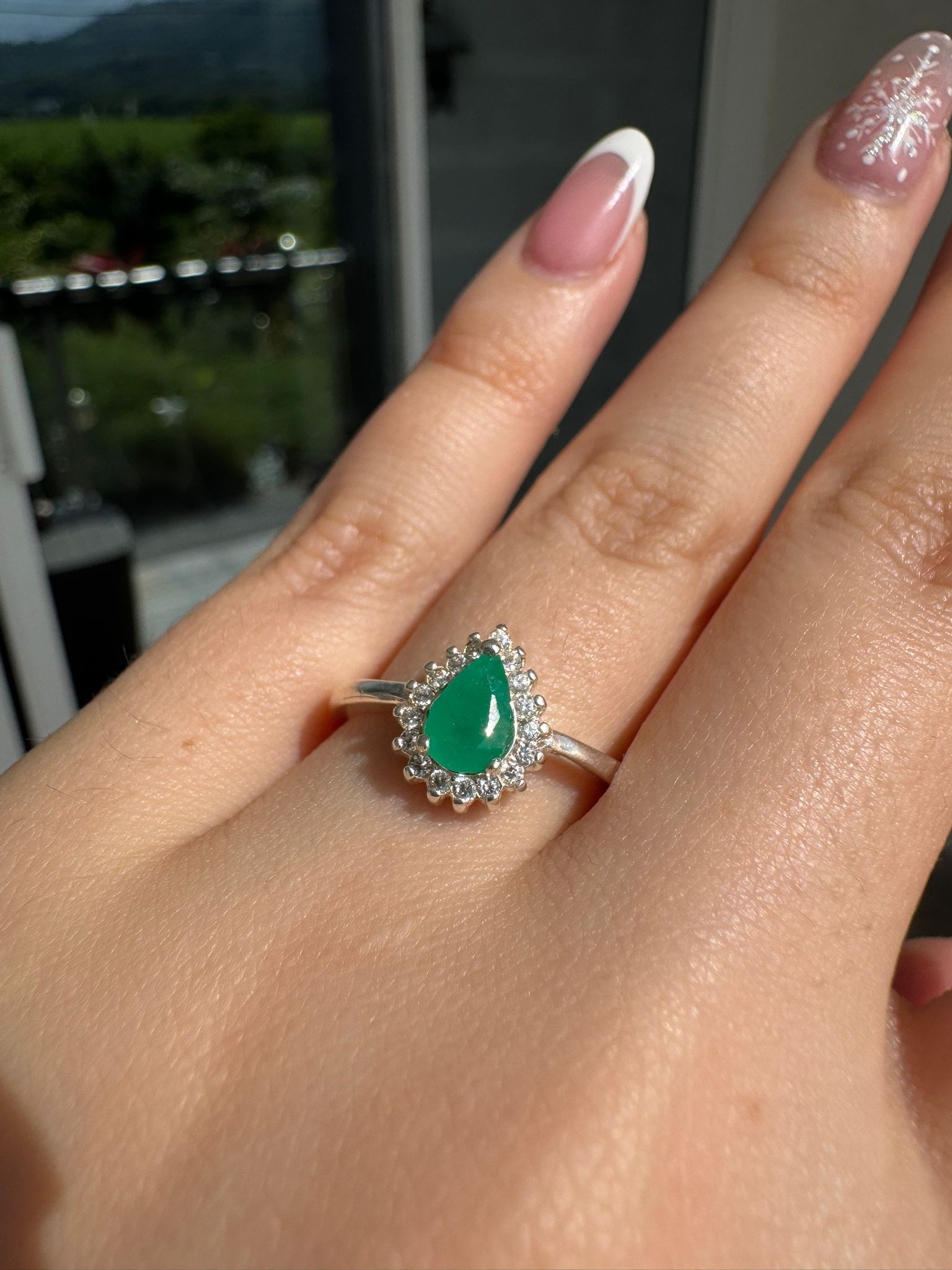 Anillo de esmeralda colombiana corte pera con halo de circonitas, puesto en la mano