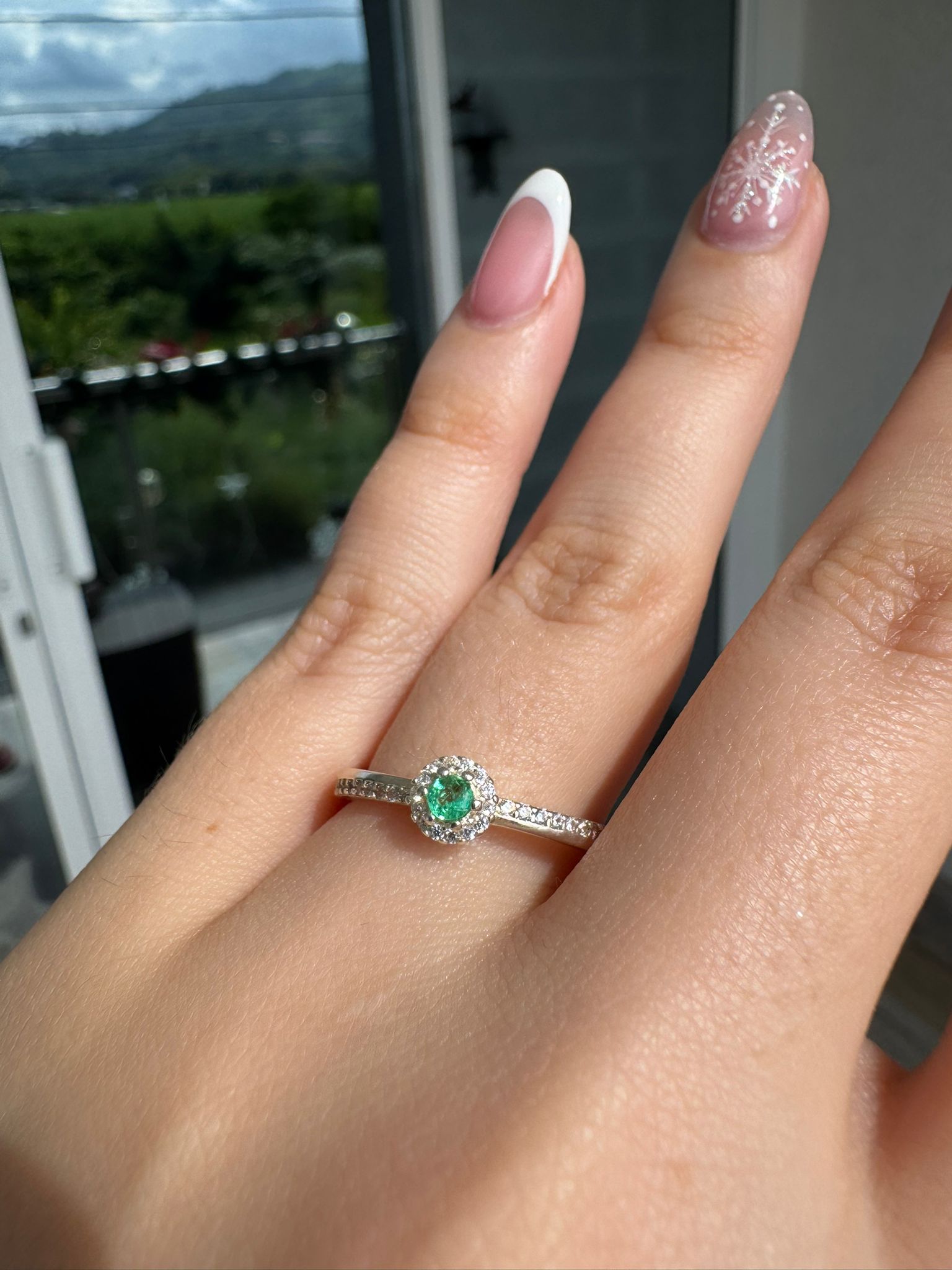 Anillo de esmeralda colombiana con halo, visto en la mano a la luz natural