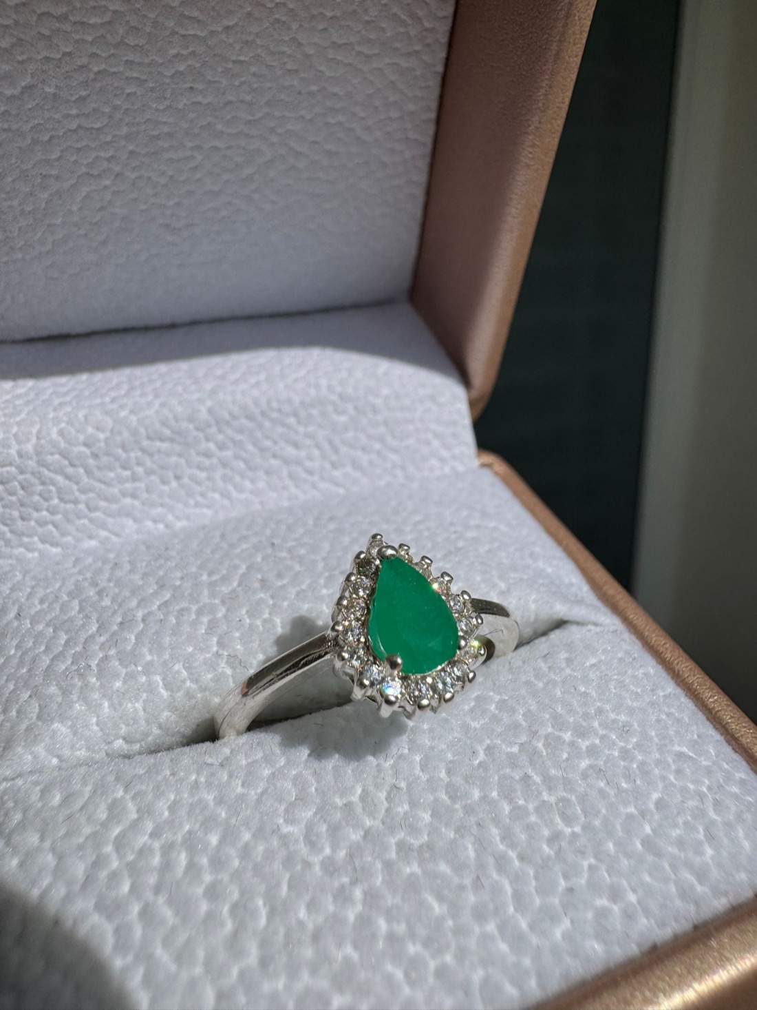Primer plano de un anillo de esmeralda colombiana con halo